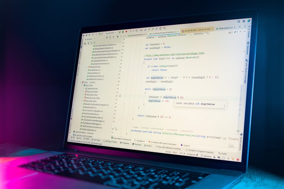 A person's hand with a wristwatch is hovering over a laptop keyboard placed on a wooden surface, with the screen displaying lines of code or text in a notepad, indicating digital work or programming a